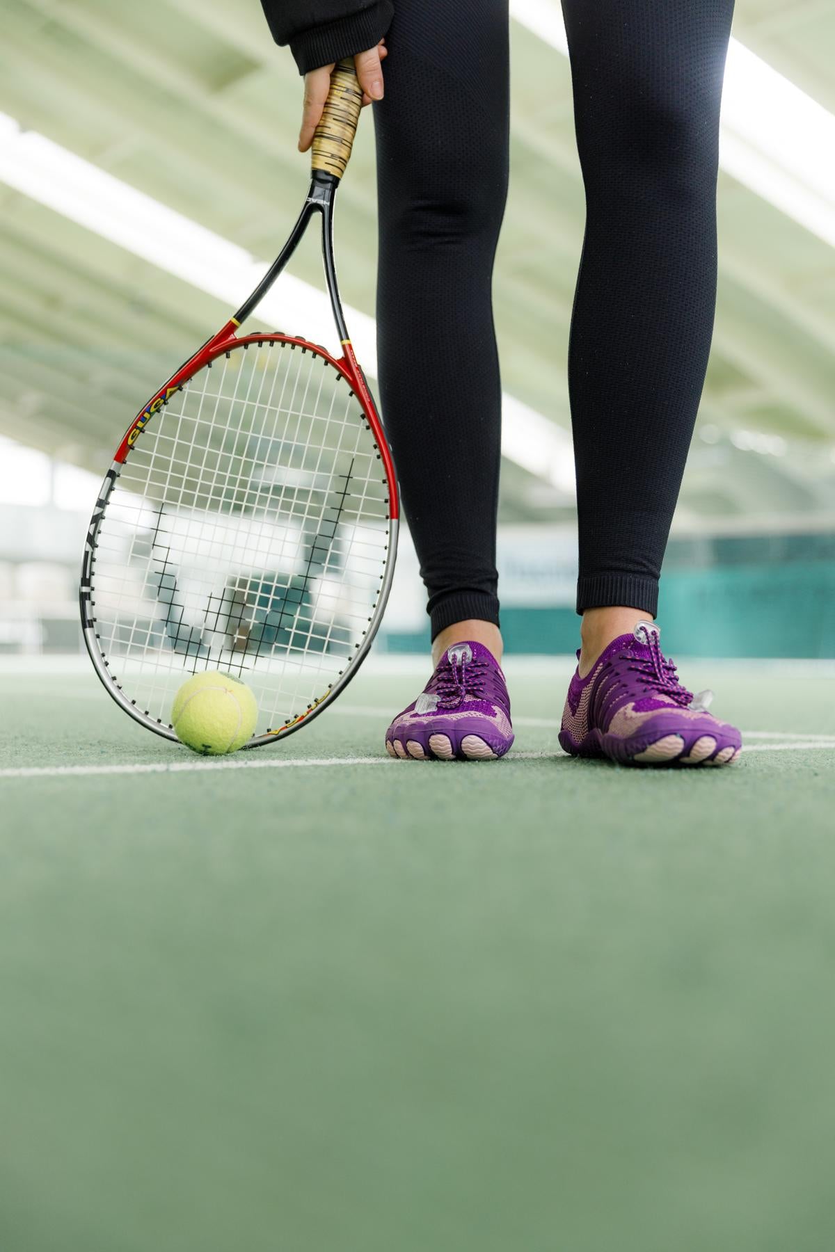 Dame mit pinken Barfußschuhen spielt tennis